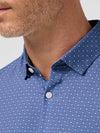 Close-up of a man wearing a blue patterned shirt with a white background