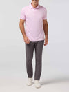 Man wearing a pink polo shirt and gray pants on a white background