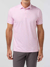 Man wearing a pink patterned polo shirt and gray pants on a light gray background
