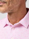Close-up of a man wearing a pink patterned shirt with a blurred background